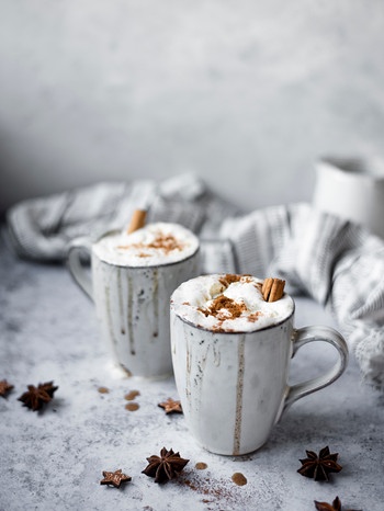 Zwei Tassen mit heißem Amaretto mit Apfelsaft und Sahne auf einem Tisch | Bild: mauritius images / The Picture Pantry / Ella Nurse