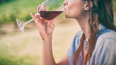 Eine Frau hält ein Glas Rotwein in der Hand  | Bild: mauritius images / Sean Prior / Alamy / Alamy Stock Photos