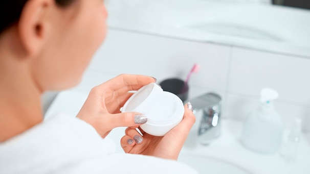 Frau hält im Badezimmer eines Hotels eine Creme-Probe in der Hand | Bild: mauritius images / Serhii Bobyk / Alamy / Alamy Stock Photos