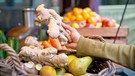 Die Hand einer Frau hält an einem Marktstand ein großes Stück Ingwerwurzelknolle in der Hand | Bild: mauritius images / Westend61 / Anthony Photography