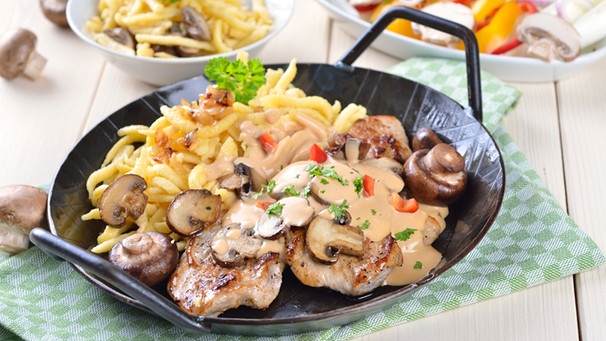 Jägerschnitzel mit Champignons angerichtet mit Spätzle in einer Pfanne | Bild: mauritius images / Karl Allgäuer