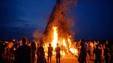 Menschen stehen um ein Johannisfeuer in Oberbayern | Bild: mauritius images / Hans Lippert / imageBROKER