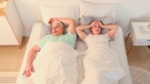 Frau liegt verzweifelt und schlaflos in einem Doppelbett neben einem Mann, der schnarcht | Bild: mauritius Bilder / Pixel-shot / Alamy / Alamy Stock Fotos