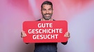 Marcus Fahn hält ein Schild in Händen auf dem steht: "Gute Geschichte gesucht" | Bild: BR/ Markus Konvalin