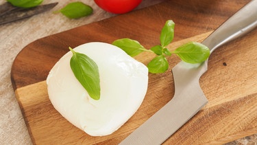 Frischer Bio-Mozzarella mit Basilikum und Tomaten in einer Küche | Bild: mauritius images / beanimages