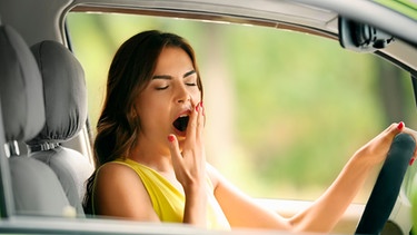 Autofahrerin gähnt am Steuer eines Autos | Bild: mauritius Bilder / Pixel-shot / Alamy / Alamy Stock Fotos