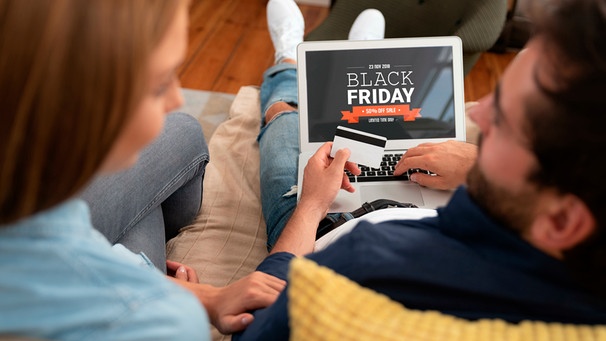 Paar sitzt auf einer Couch und shoppt an einem Laptop online Angebote zum Black Friday | Bild: mauritius images / Piotr Adamowicz / Alamy / Alamy Stock Fotos