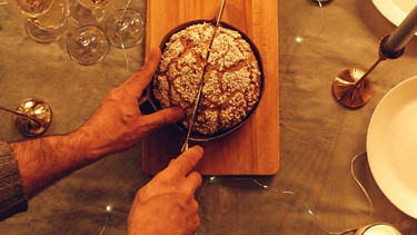 Eine Hand schneidet Panettone auf | Bild: mauritius images / Dasha Petrenko / imageBROKER