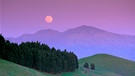 Über den Bergen geht ein rosafarbener Mond auf | Bild: mauritius images / Brad Perks Lightscapes / Alamy / Alamy Stock Photos