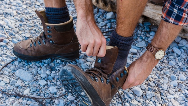 Mann zieht sich Wanderschuhe an | Bild: mauritius images / Westend61 / Daniel Ingold