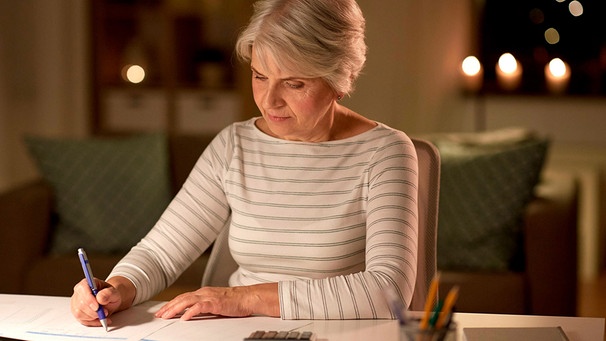 Eine Frau sitzt an einem Tisch mit Laptop und Taschenrechner  | Bild: mauritius images / Lev Dolgachov / Alamy / Alamy Stock Fotos