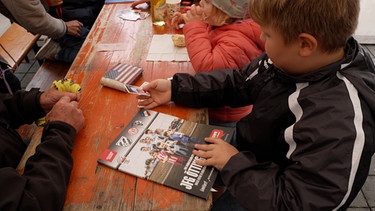 Ein Junge sitzt an einem Tisch mit dem Album und Stickerbildern | Bild: Privat