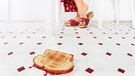 Heruntergefallener Marmeladentoast liegt auf dem Boden in einer Küche, dahinter die Füße einer Frau | Bild: mauritius images / Thomas Schultze / Volume3