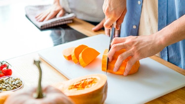 Hände eines Mannes beim Schneiden eines Butternut-Kürbisses | Bild: mauritius images / Prostock-studio / Alamy / Alamy Stock Photos