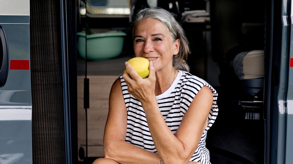 Eine Frau isst einen Apfel. | Bild: mauritius images / Westend61 / FL