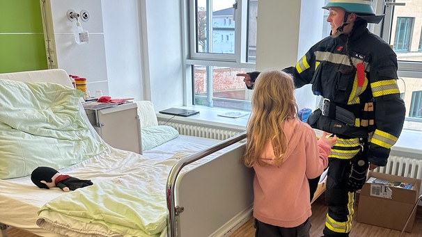 Ein kleines Mädchen bekommt im Krankenhaus Besuch von den Flammenfreunden Oberhausen von der Freiwilligen Feuerwehr | Bild: Freiwillige Feuerwehr Oberhausen