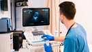 Arzt in einem Krankenhaus an einem Ultraschallgerät | Bild: mauritius images / Westend61 / Mario Martinez