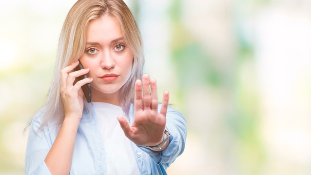 Frau mit Handy am Ohr macht eine Geste der Abwehr  | Bild: mauritius images / Aaron Amat / Alamy / Alamy Stock Photos