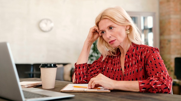 Eine Frau blickt besorgt auf ihren Computer | Bild: mauritius images / Dmitriy Shironosov / Alamy / Alamy Stock Photos