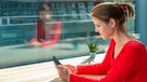 Eine Frau sitzt an einem Fenster und hat ein Smartphone in der Hand | Bild: mauritius images / Bohemama / Alamy / Alamy Stock Photos