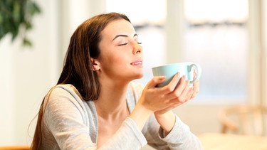 Frau hält eine Tasse mit Kaffee in den Händen und genießt sie mit geschlossenen Augen | Bild: mauritius images / Antonio Guillem Fernández / Alamy / Alamy Stock Photos