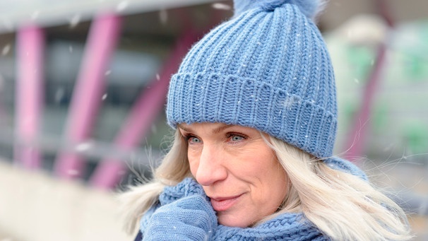 Eine Frau mit Wintermütze steht draußen, Portrait, es schneit. | Bild: mauritius images / Michael Heim / Alamy / Alamy Stock Photos