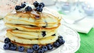 Symbolbild: Ein Haufen herrlich leckere Pancakes mit Blaubeeren und Agavendicksaft | Bild: mauritius images / YAY Media AS / Alamy / Alamy Stock Photos