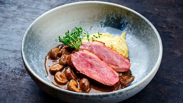 Ein schöner, tiefer Teller mit Polenta, karamellisierten Pilzen und Entenbrust rosa gebraten | Bild: mauritius images / Zoonar GmbH / Alamy / Alamy Stock Photos