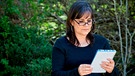 Eine Frau mit einer Lesebrille liest im Garten  | Bild: mauritius images / Pamela Au / Alamy / Alamy Stock Photos