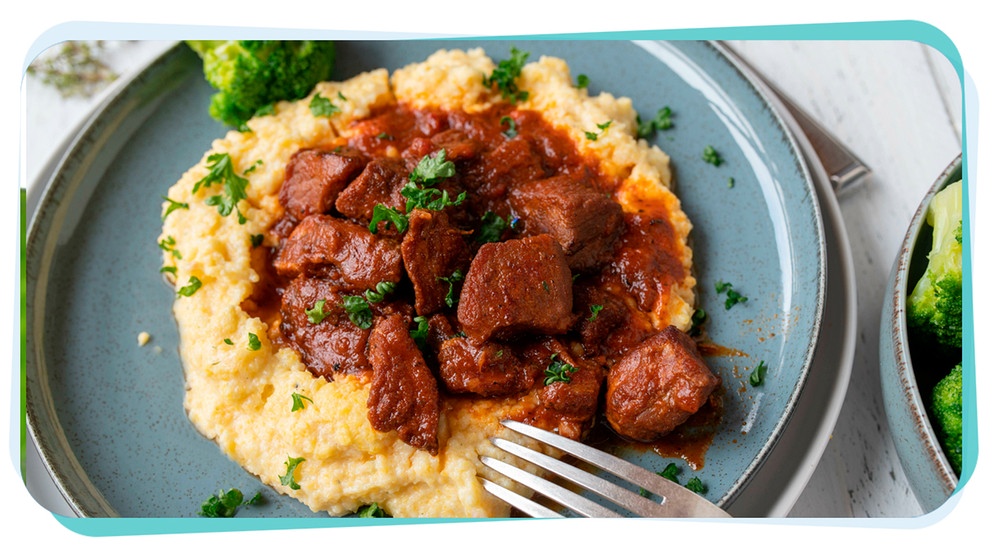 Saftiges Rindergulasch. serviert in einem tiefen Teller auf Polenta | Bild: mauritius images / Angelika Heine / Alamy / Alamy Stock Photos, Montage: BR