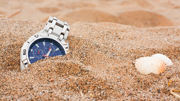 Uhr liegt am Strand halb verdeckt im Sand | Bild: mauritius images  Stocksolutions  Alamy  Alamy Stock Photos