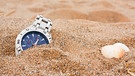 Uhr liegt am Strand halb verdeckt im Sand | Bild: mauritius images  Stocksolutions  Alamy  Alamy Stock Photos