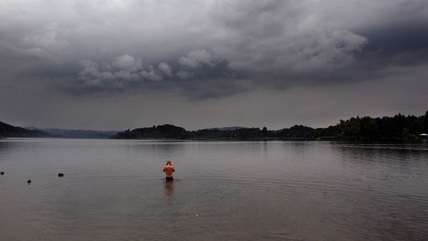 Mann steht im See, während ein Gewitter aufzieht. | Bild: picture-alliance dpa  Karl-Josef Hildenbrand