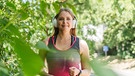 Frau joggt mir Kopfhörern durch einen Park | Bild: mauritius images  Westend61  Ok Shu