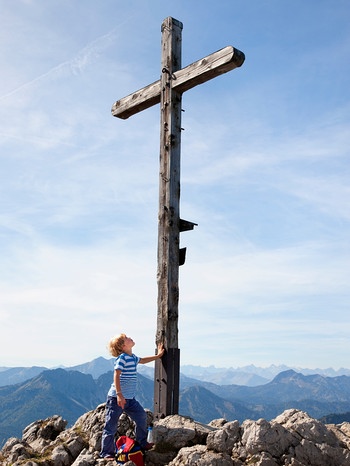 Junge berührt Gipfelkreuz | Bild: mauritius images / Westend61 / hsimages