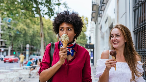 Zwei Frauen essen Eis. Eine ist sehr munter und zugetan, die andere ist verhalten und abgewandt | Bild: mauritius images  Cavan Images