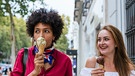 Zwei Frauen essen Eis. Eine ist sehr munter und zugetan, die andere ist verhalten und abgewandt | Bild: mauritius images  Cavan Images