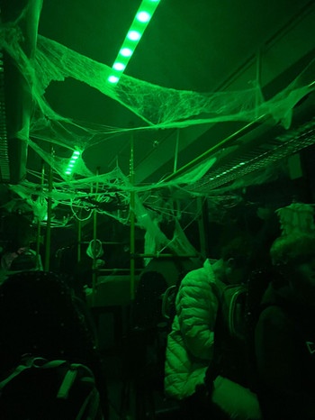 Ein Schulbus ist von innen zu sehen, draußen ist es stockdunkel, innen ist der Bus neongrün beleuchtet. Man sieht Spinnweben und gruselige Deko. Passend zu Halloween. | Bild: privat