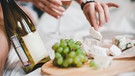 Appetitlicher Käse auf einem Brett, daneben ein Glas Wein | Bild: mauritius images / Aleksey Serikov / Alamy / Alamy Stock Photos