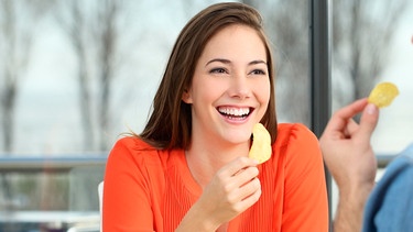 Eine junge Frau isst Kartoffelchips | Bild: mauritius images / Antonio Guillem Fernández / Alamy / Alamy Stock Photos