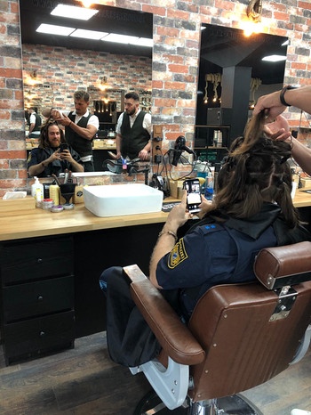 Polizist Marco Dinaro sitzt beim Friseur, seine Haare werden für die Spende vorbereitet. | Bild: Privat