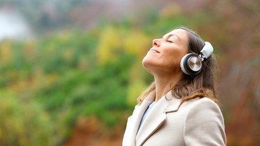 Eine hört über Kopfhörer Musik und wirkt dabei sehr zufrieden und geerdet | Bild: mauritius images / Antonio Guillem Fernández / Alamy / Alamy Stock Photos