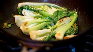 In einem Wok wird Pak Choi zubereitet. | Bild: mauritius images / foodcollection