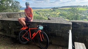 Pause mit dem Gravelbike mit Ausblick auf die Burg von Königsberg in den Haßbergen. | Bild: BR/Achim Winkelmann