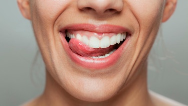 Frau schleckt sich über ihre Weißen Zähne | Bild: mauritius images  Nikola Spasenoski  Alamy  Alamy Stock Photos