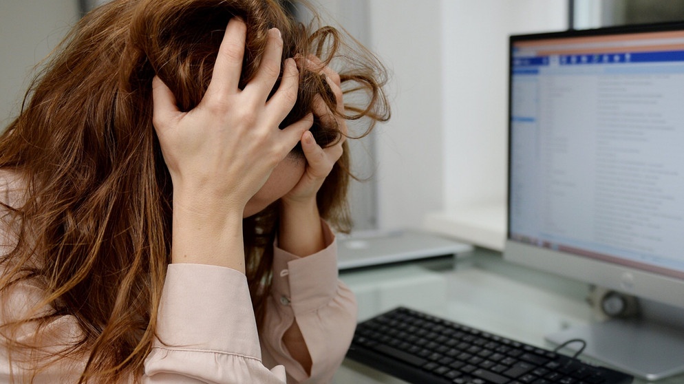 Eine junge Frau sitzt gestresst in ihrem Büro zu Hause. | Bild: picture alliance / Frank May | Frank May