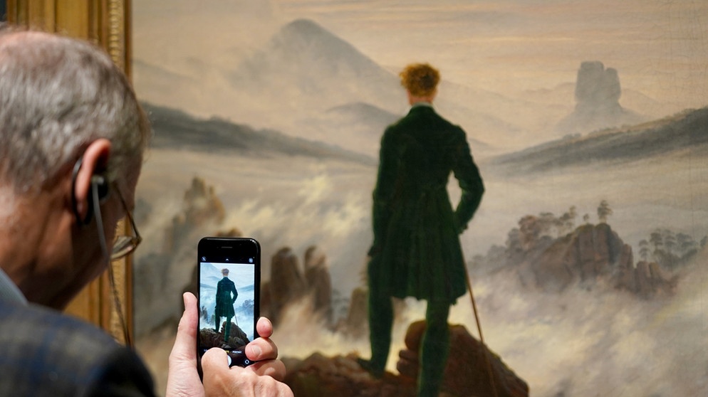 Ein Mann fotografiert das Werk "Wanderer über dem Nebelmeer" von Caspar David Friedrich in der Hamburger Kunsthalle. Im Jubiläumsjahr zum 250. Geburtstag von Caspar David Friedrich (1774-1840) gibt es dort eine große Retrospektive zu sehen. | Bild: dpa-Bildfunk/Marcus Brandt