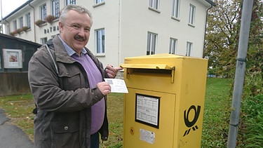 Martin Kreuzer wirft die letzte Postkarte der Fernschachgeschichte in seinen Briefkasten in Niederbayern. | Bild: BR/Thibaud Schremser