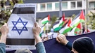 Pro-Israelischer Gegendemonstrant zeigt eine jüdische Zeitung mit einem Davidstern, im Hintergrund Pro-Palästinensische Demonstranten (Veranstaltung im Düsseldorf am 14. Oktober 2023) | Bild: picture-alliance/dpa