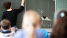 Eine Lehrerin schreibt in einer Grundschule Wörter mit «Sp» am Anfang an eine Tafel. | Bild: dpa-Bildfunk/Sebastian Gollnow